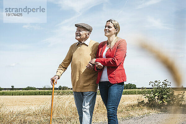 Happy woman holding hand of senior man on sunny day