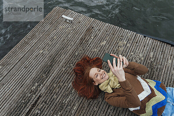 Lächelnde Frau benutzt Smartphone  das am Pier liegt