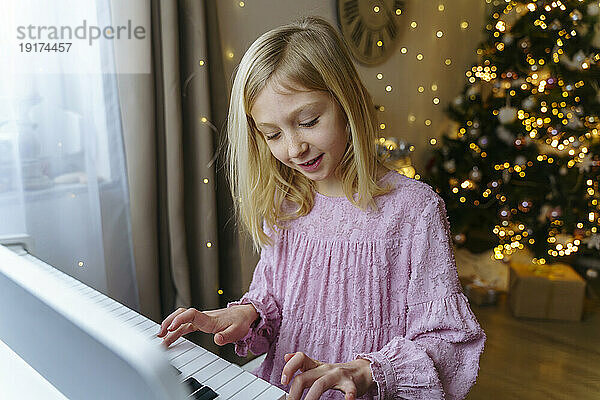 Mädchen spielt an Weihnachten zu Hause Klavier