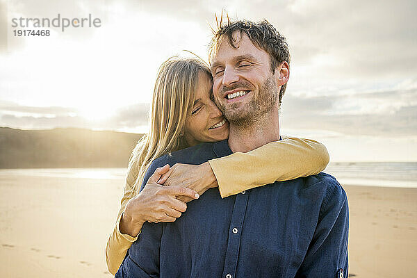 Lächelnde Frau umarmt Mann an sonnigem Tag