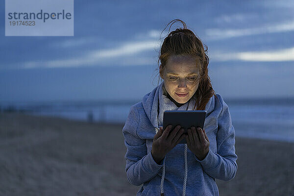 Frau benutzt Tablet-PC am Strand
