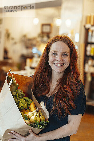 Happy redhead woman doing grocery shopping at store