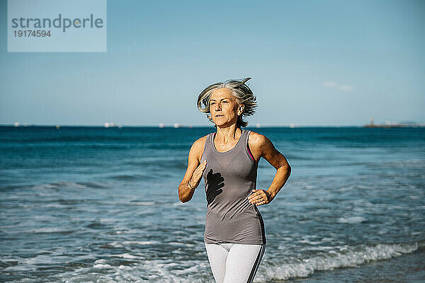 Reife Frau joggt am Strand