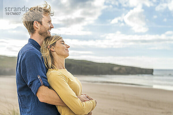 Glücklicher Mann steht mit Frau am Strand