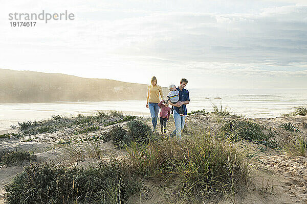 Happy family walking in front of sea at beach