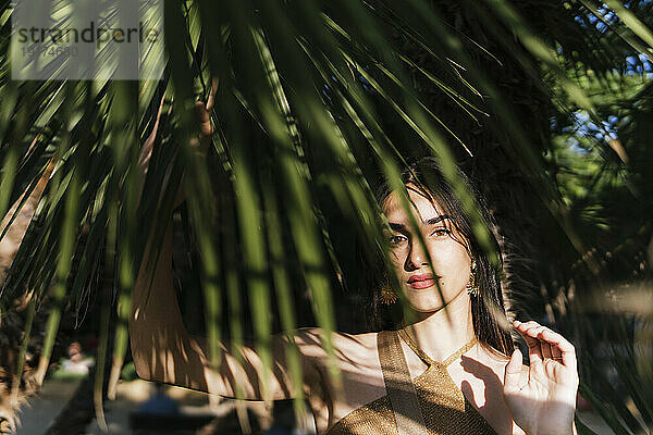 Junge Frau zwischen Palmblättern an einem sonnigen Tag