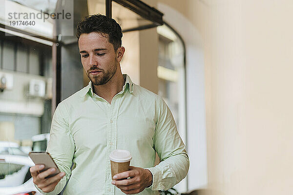 Junger Geschäftsmann benutzt Smartphone im Café