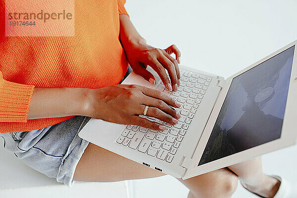 Junge Frau kauft online über Laptop im Studio ein