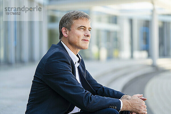 Serene businessman sitting in front of modern office building