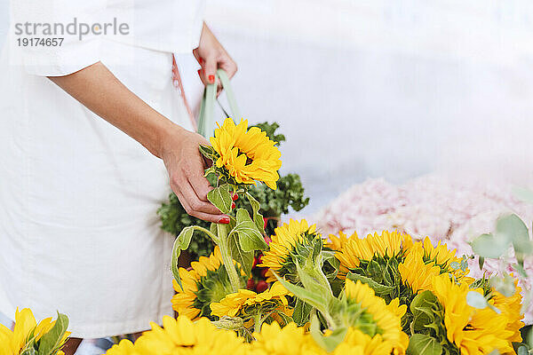 Frau kauft gelbe Blumen auf dem Markt