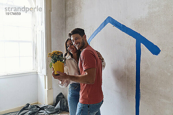 Glücklicher Mann und Frau halten Blumenstrauß vor der Wand vor Ort