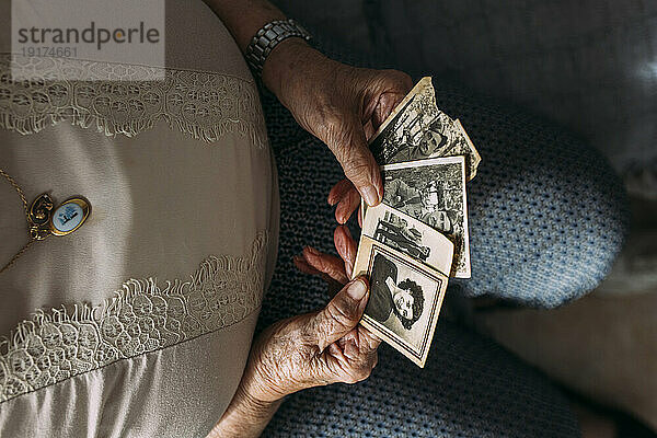 Senior woman holding photographs from past at home