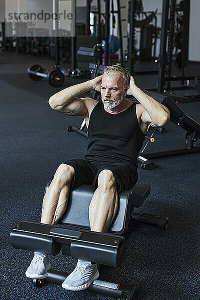 Reifer Mann trainiert an Geräten im Fitnessstudio