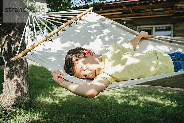 Boy relaxing on hammock in front of house