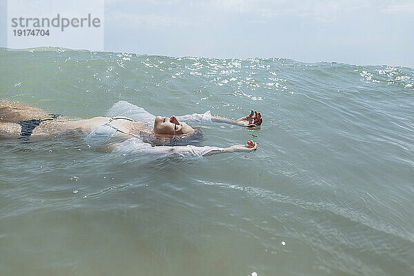 Frau im Bikini schwimmt auf dem Wasser im Meer