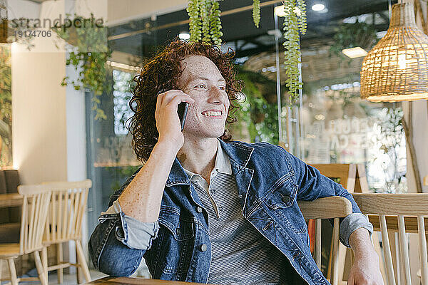 Glücklicher Mann  der im Café mit dem Handy spricht
