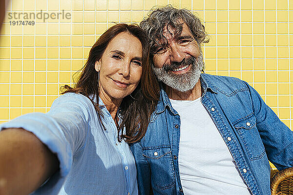 Lächelndes älteres Paar  das an einem sonnigen Tag ein Selfie macht