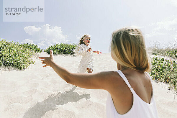Glückliche Tochter rennt am Strand auf Mutter zu