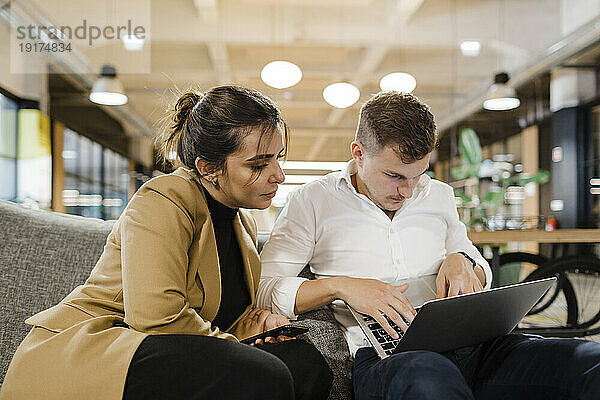 Konzentrierte Geschäftskollegen arbeiten im Büro am Laptop