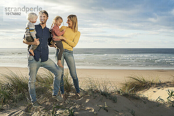Glücklicher Vater und Mutter mit Kindern am Strand
