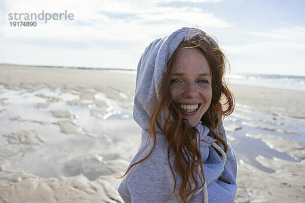 Happy woman wearing hooded shirt at beach on vacation