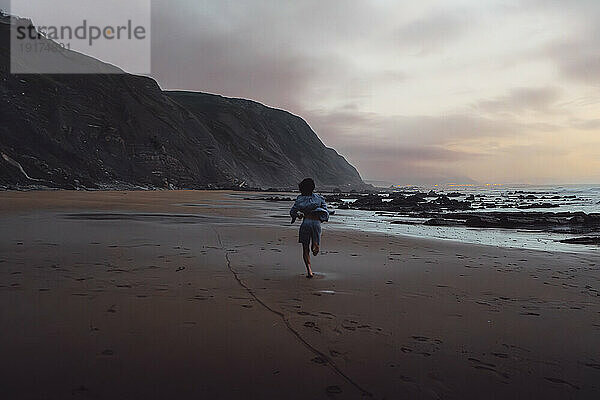 Junger Mann läuft auf Sand am Strand