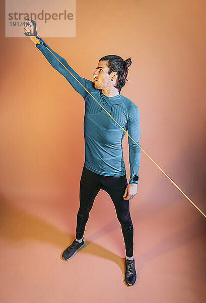 Man stretching with resistance band in front of backdrop