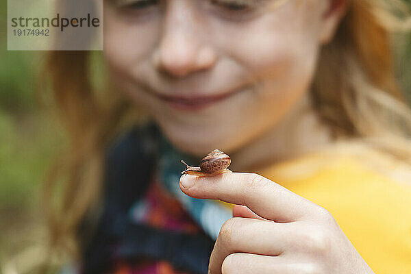 Girl with small snail on finger