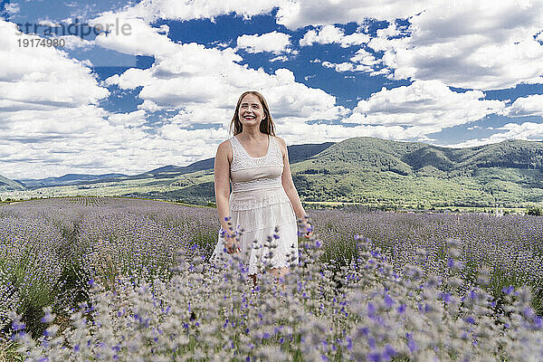 Glückliche Frau  die inmitten von Lavendelblüten im Feld spaziert