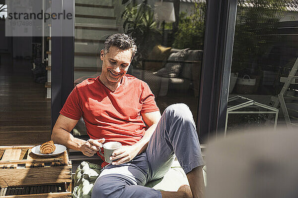 Man relaxing on balcony with mug in hand