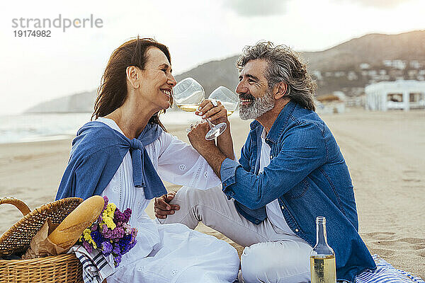 Glückliches älteres Paar  das am Strand Wein aus Weingläsern trinkt