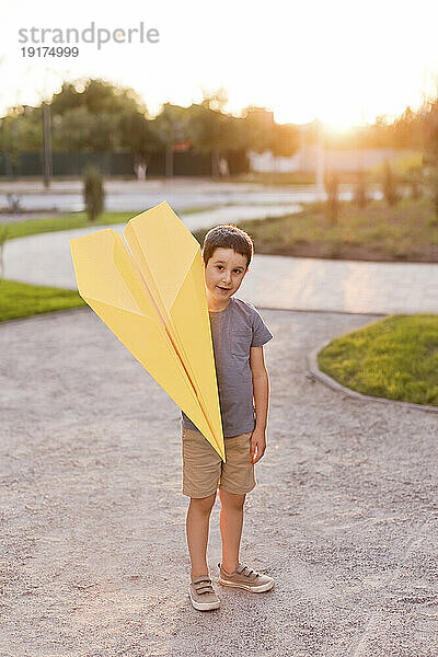 Junge hält Papierflieger im Park