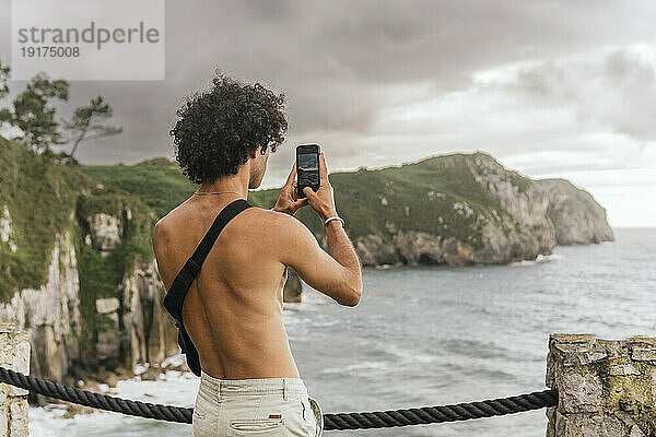 Mann fotografiert Meer mit Smartphone
