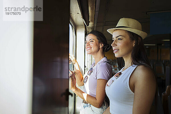 Lächelnde Freunde  die im Zug reisen