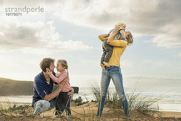 Glückliche Familie  die sich am Strand umarmt
