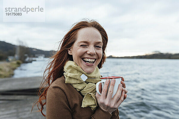 Glückliche Frau mit Teetasse am See