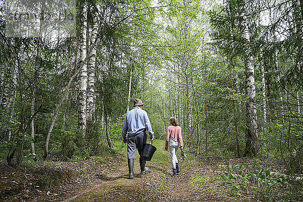 Älterer Mann geht mit seiner Enkelin im Wald spazieren