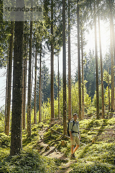 Man hiking by trees in forest