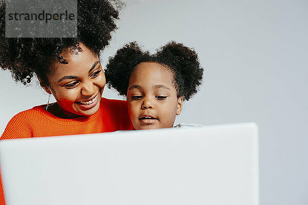 Mutter und Tochter nutzen gemeinsam Laptop im Studio