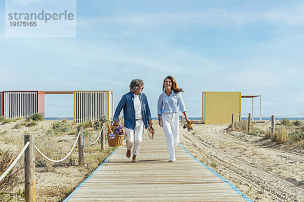 Glückliches älteres Paar mit Picknickkorb  das am Strand läuft