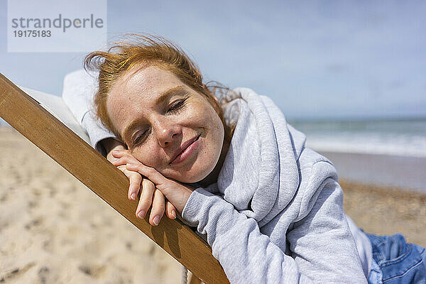 Woman relaxing on deck chair at beach