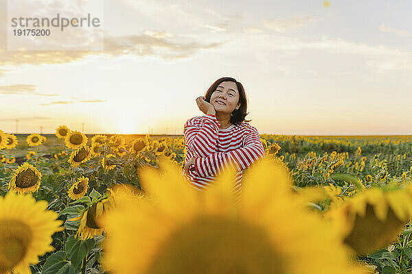 Reife Frau inmitten von Sonnenblumen im Feld