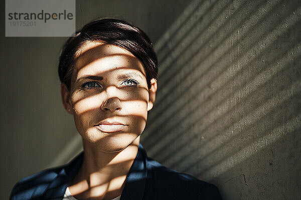 Geschäftsfrau mit Schatten im Gesicht vor der Wand