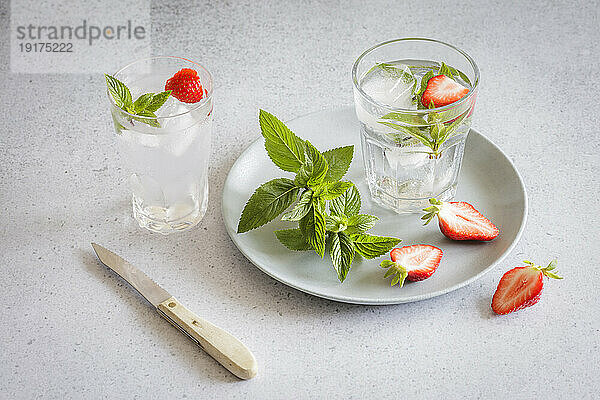 Studioaufnahme von Gläsern angereichertem Wasser mit Minze und Erdbeeren