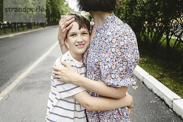 Glücklicher Junge umarmt Mutter auf der Straße