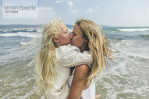 Mädchen küsst Mutters Nase am Strand