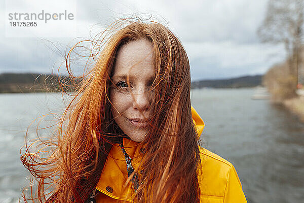 Rothaarige Frau mit langen Haaren vor dem See