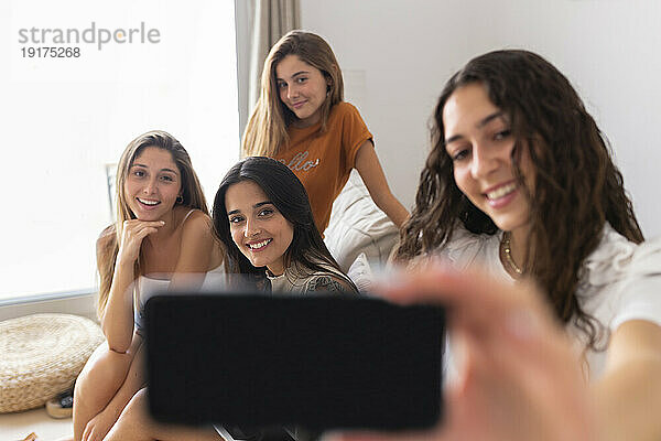 Glückliche Freunde  die zu Hause auf dem Sofa sitzend ein Selfie machen