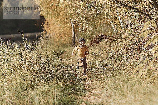 Cheerful boy running amidst plants