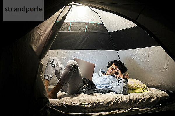 Man using laptop in tent